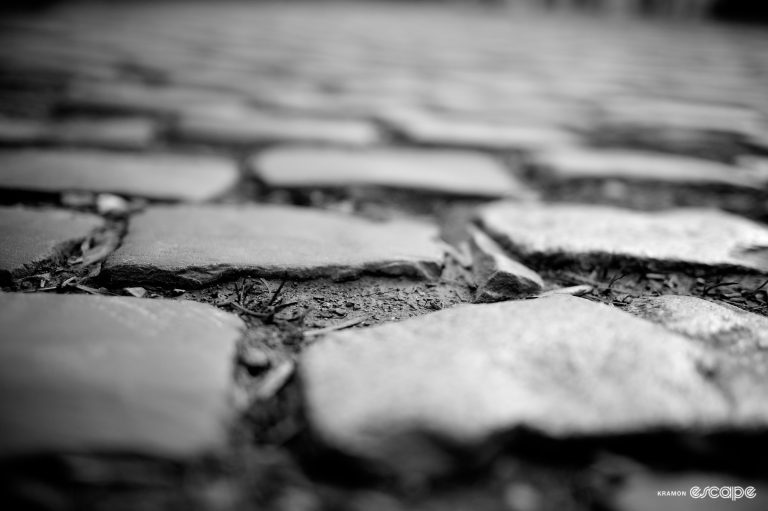 Grey cobbles are shown in close-up: large, irregular stones with rough, sharp edges and spacious gaps between.