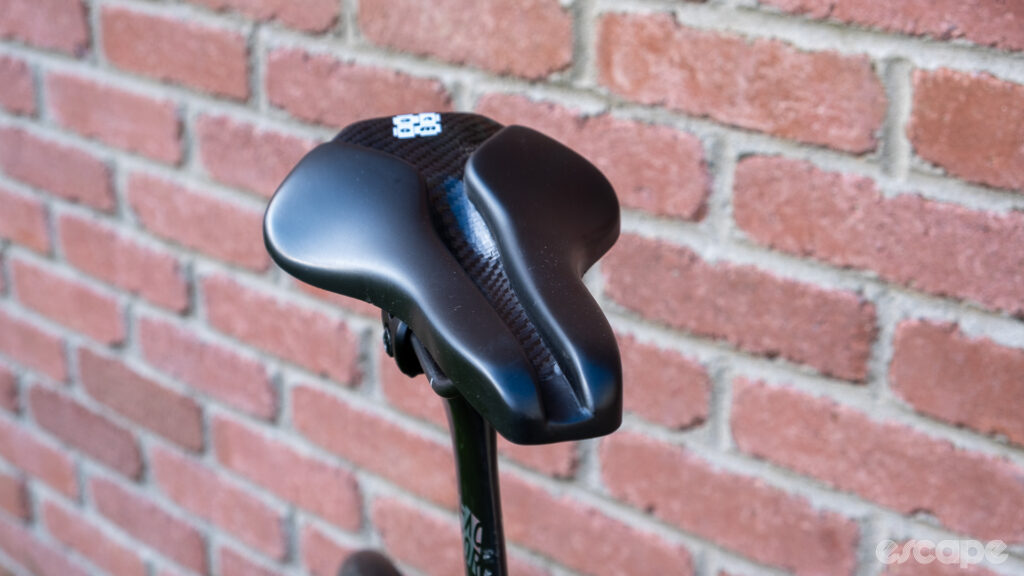 The image shows the central channel and twin-style nose on a Wove Mags carbon fibre bike saddle.