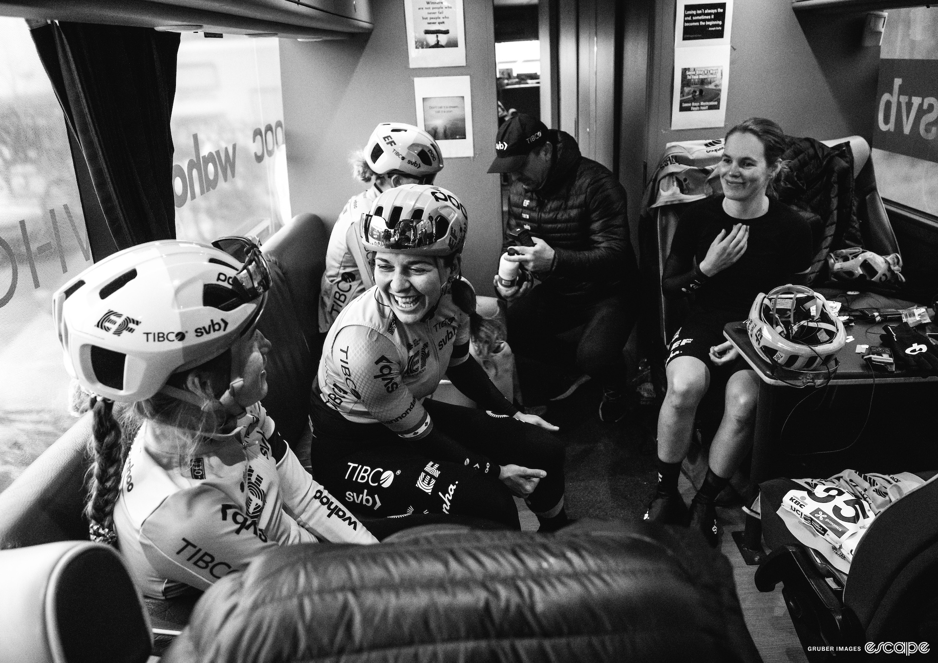 Alison Jackson sits with her EF-TIBCO-SVB teammates as they sit on a camper bus. They are all laughing together. 