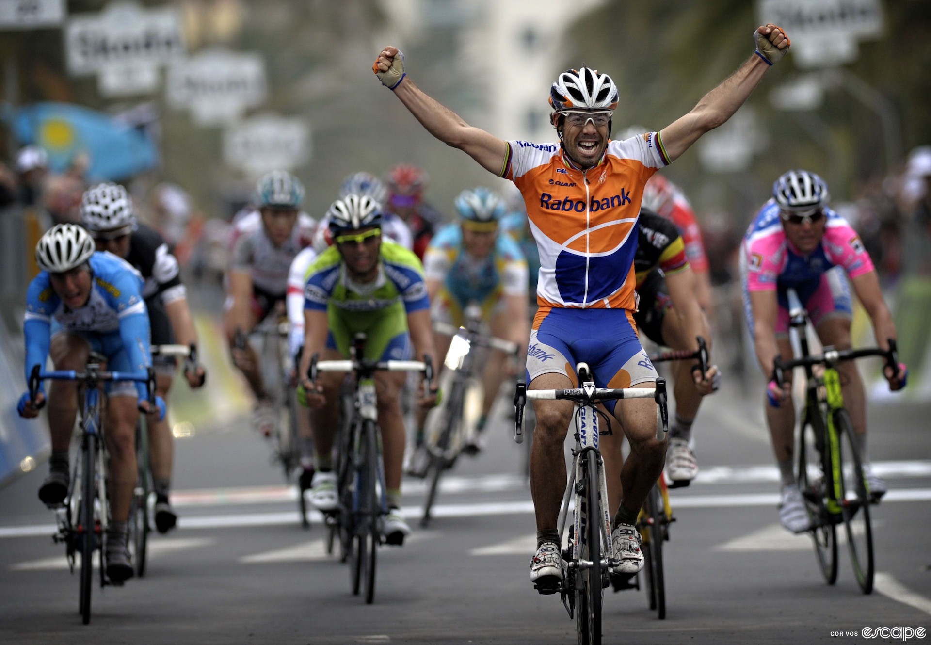 Óscar Freire wins Milan-San Remo, one of three times he did so as a pro. He is at the front of a field of riders, arms raised as he crosses the line well in front of his sprint rivals.