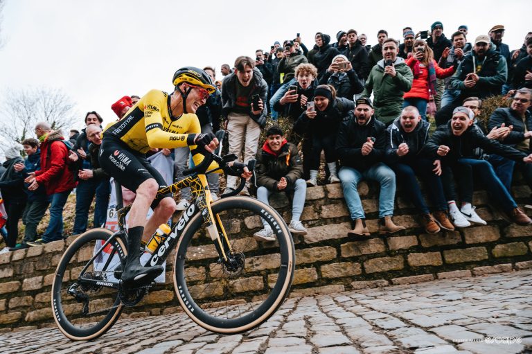 Matteo Jorgenson climbs the Muur de Geraardsbergen at the 2024 Omloop Het Nieuwsblad. He's alone, in the saddle on the steep cobbles, with fans on the climb cheering him on.