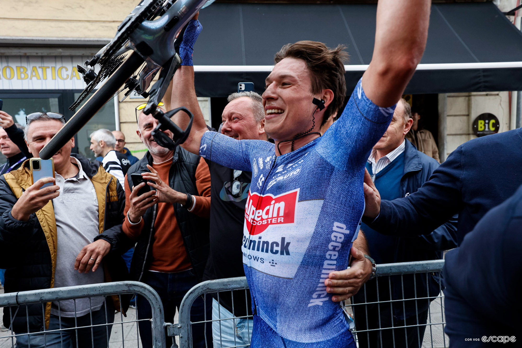 Jasper Philipsen lifts his bike aloft in celebration after Milan-San Remo 2024.
