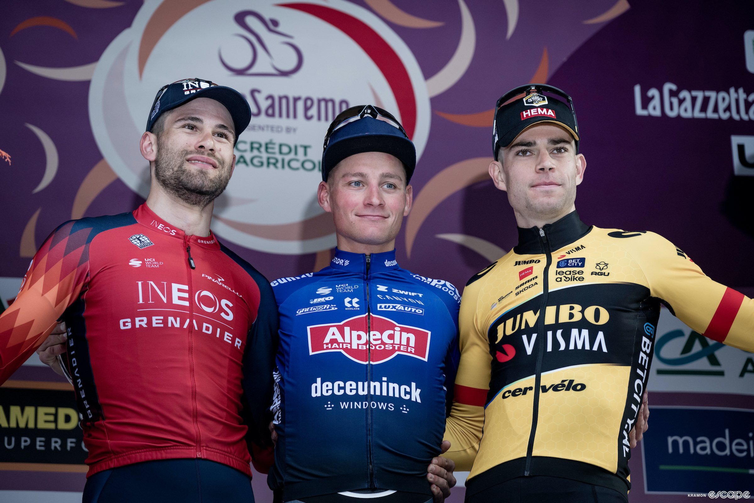 From left, Filippo Ganna, Mathieu van der Poel, and Wout van Aert stand on the podium of the 2023 Milan-San Remo. Van der Poel has a slight smile, while Ganna and Van Aert have more pensive expressions.