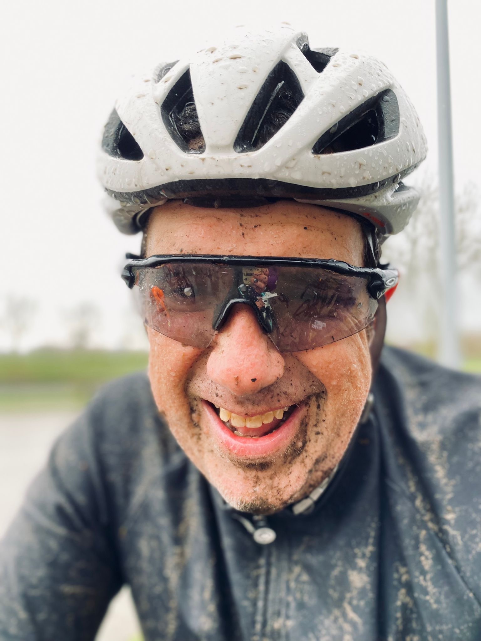 A portrait of Joey D'Antoni, face spackled with mud and dirt from riding in the rain