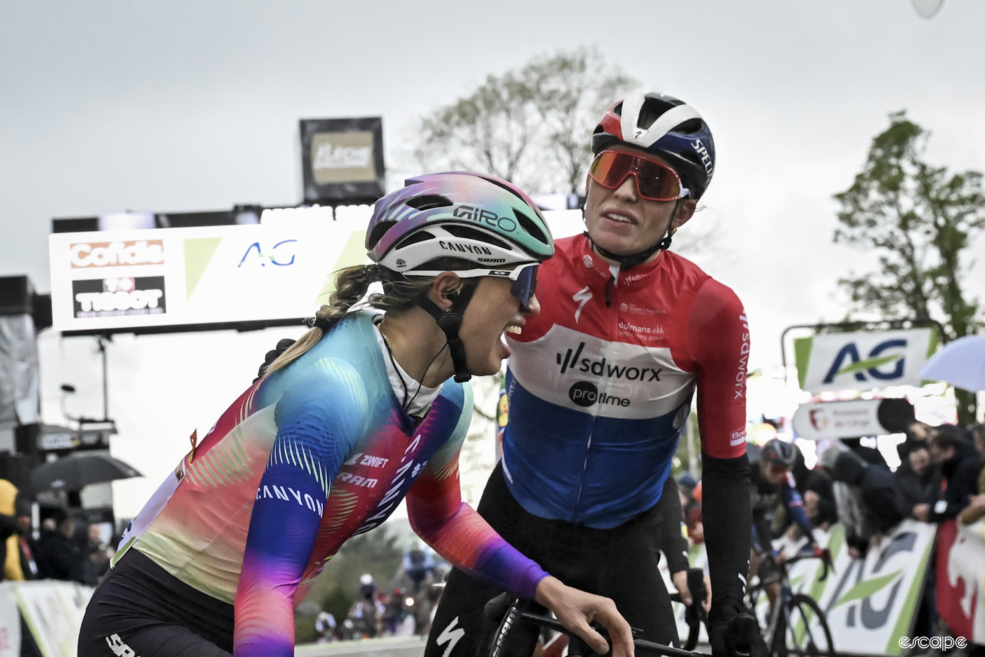 Demi Vollering congratulates Kasia Niewiadoma on her Fleche Wallonne win. Kasia is laughing and crying at the same time while Vollering pats her on the back.