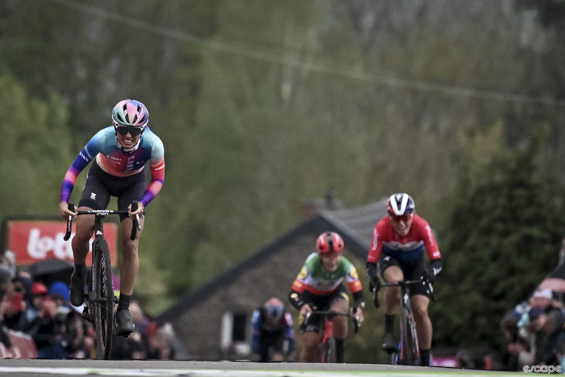 Kasia Niewiadoma grimaces from the effort as she tops the Mur de Huy climb at the 2024 Fleche Wallonne. The finish line is just meters in front of her. Behind, too far back to close the gap, Demi Vollering and Elisa Longo Borghini chase.