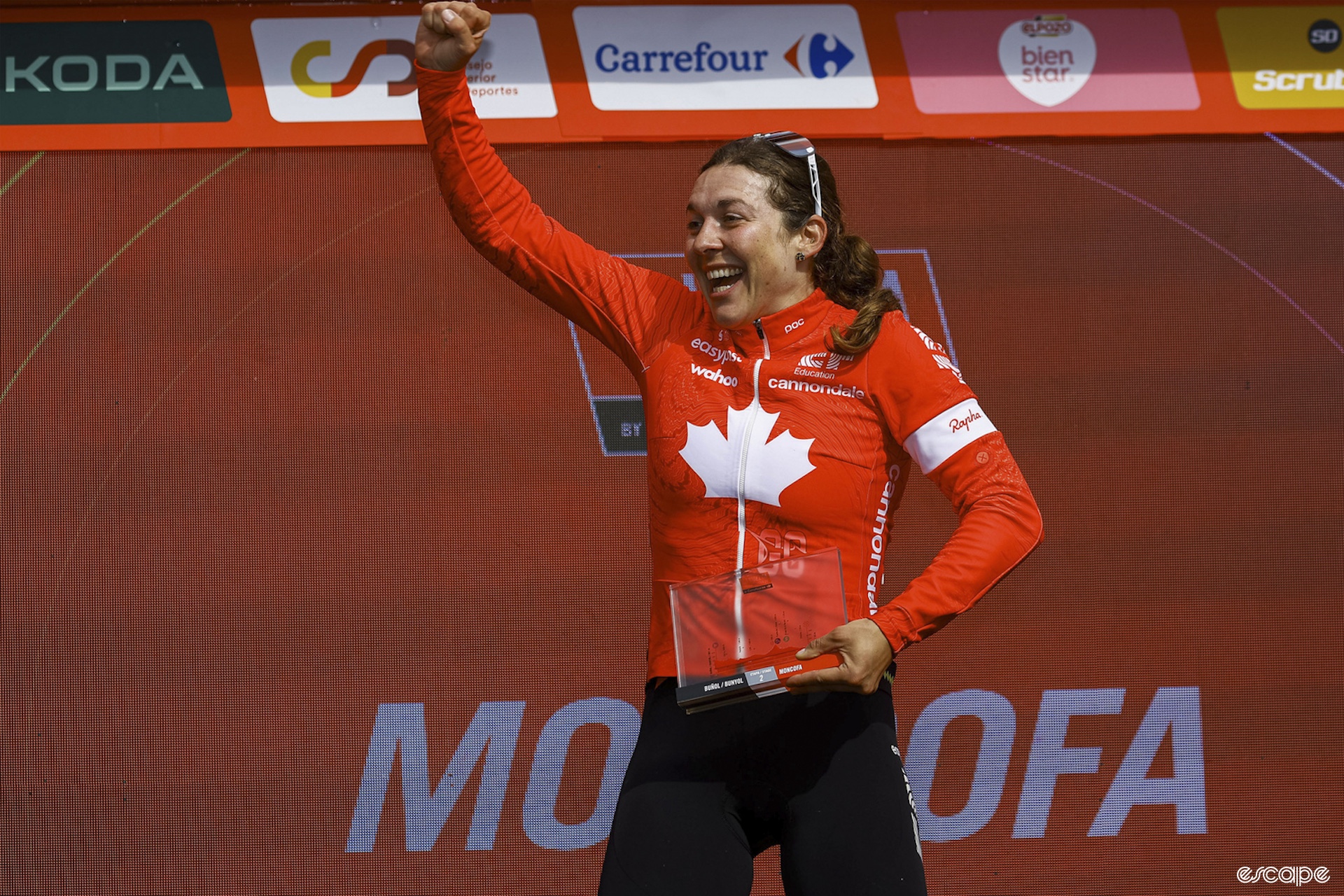 Alison Jackson wears her Canadian flag jersey as she stands on a podium to collect her stage-win prize.