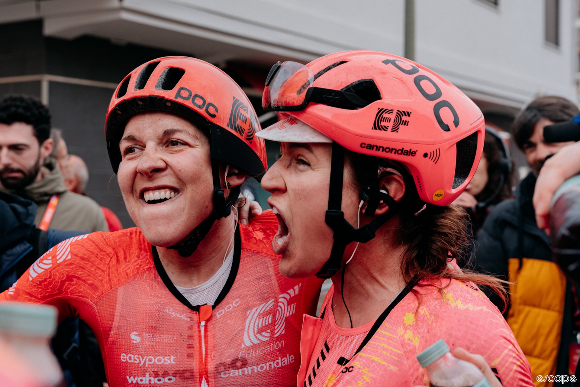 Alison Jackson and an EF teammate let out excited yells as they celebrate Jackson's stage win. Both riders have fierce expressions.