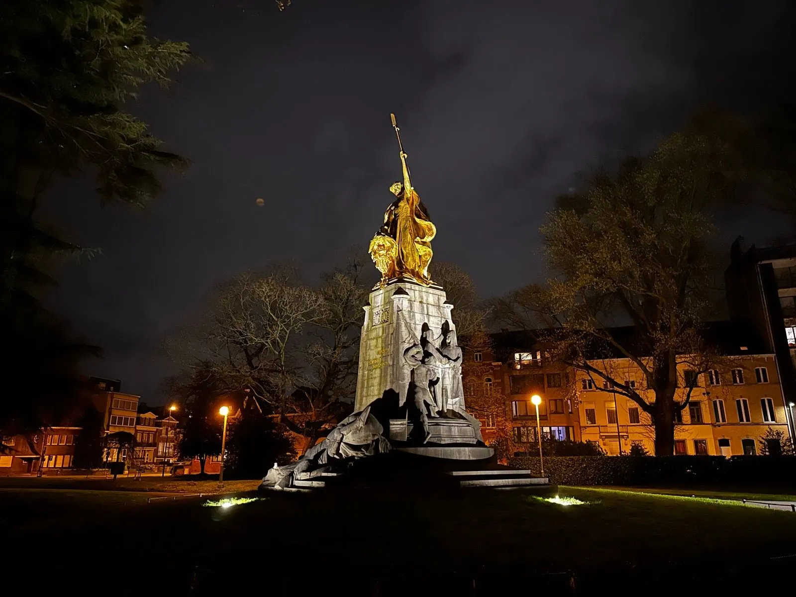 A large statue in a park, illuminated at night