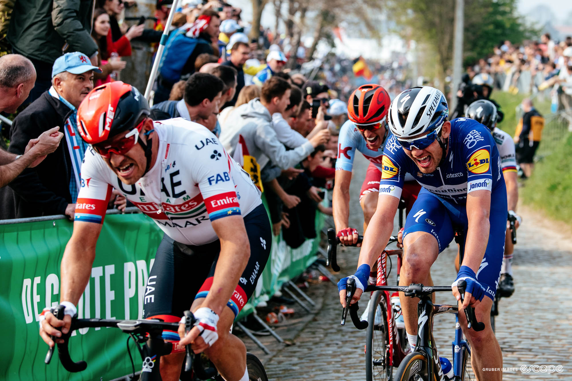 Alexander Kristoff and Kasper Asgreen fight to climb the Oude Kwaremont, mouths open from the effort and clearly straining.