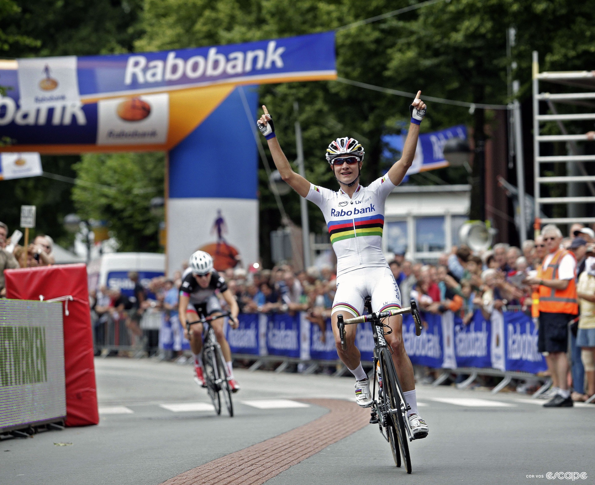 A woman raises her arms in victory as she wins a bike race