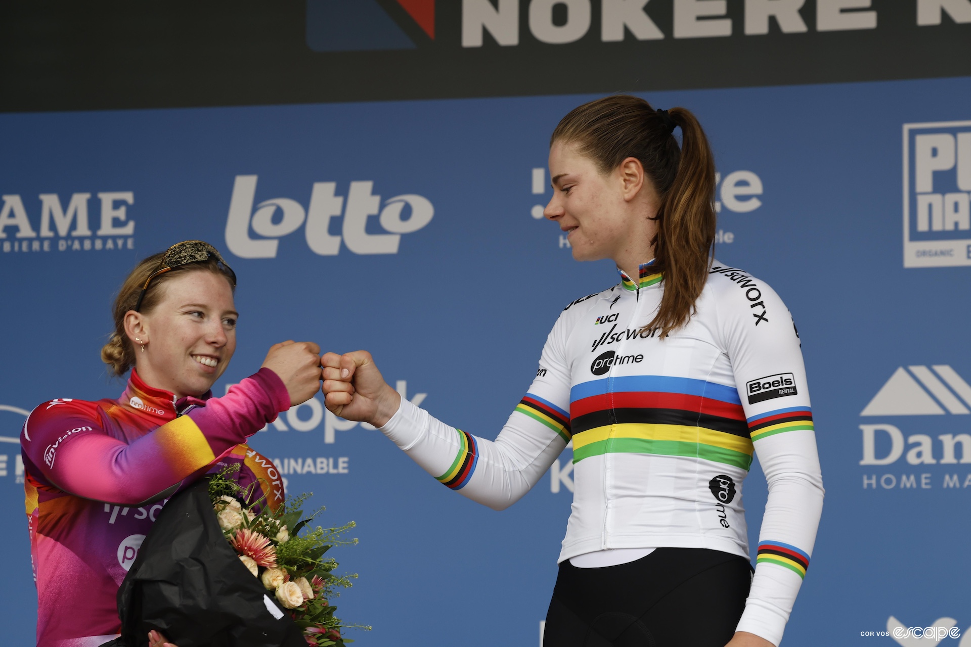 Two women fist bump on the podium of a cycling race