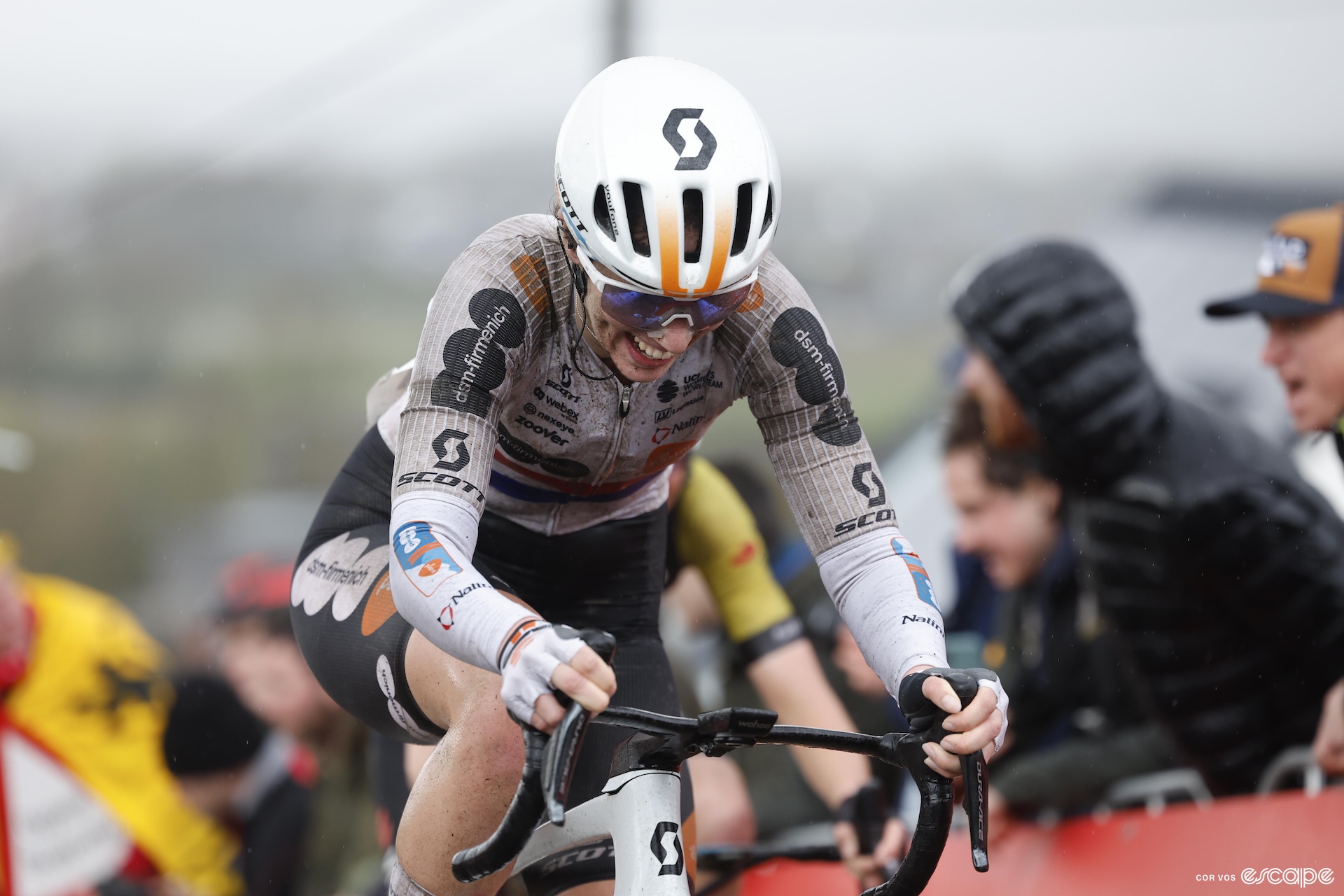 Pfeiffer Georgi digs deep to climb a section of cobbles at the Tour of Flanders. Her white DSM kit is covered in grey-brown dirt and mud.