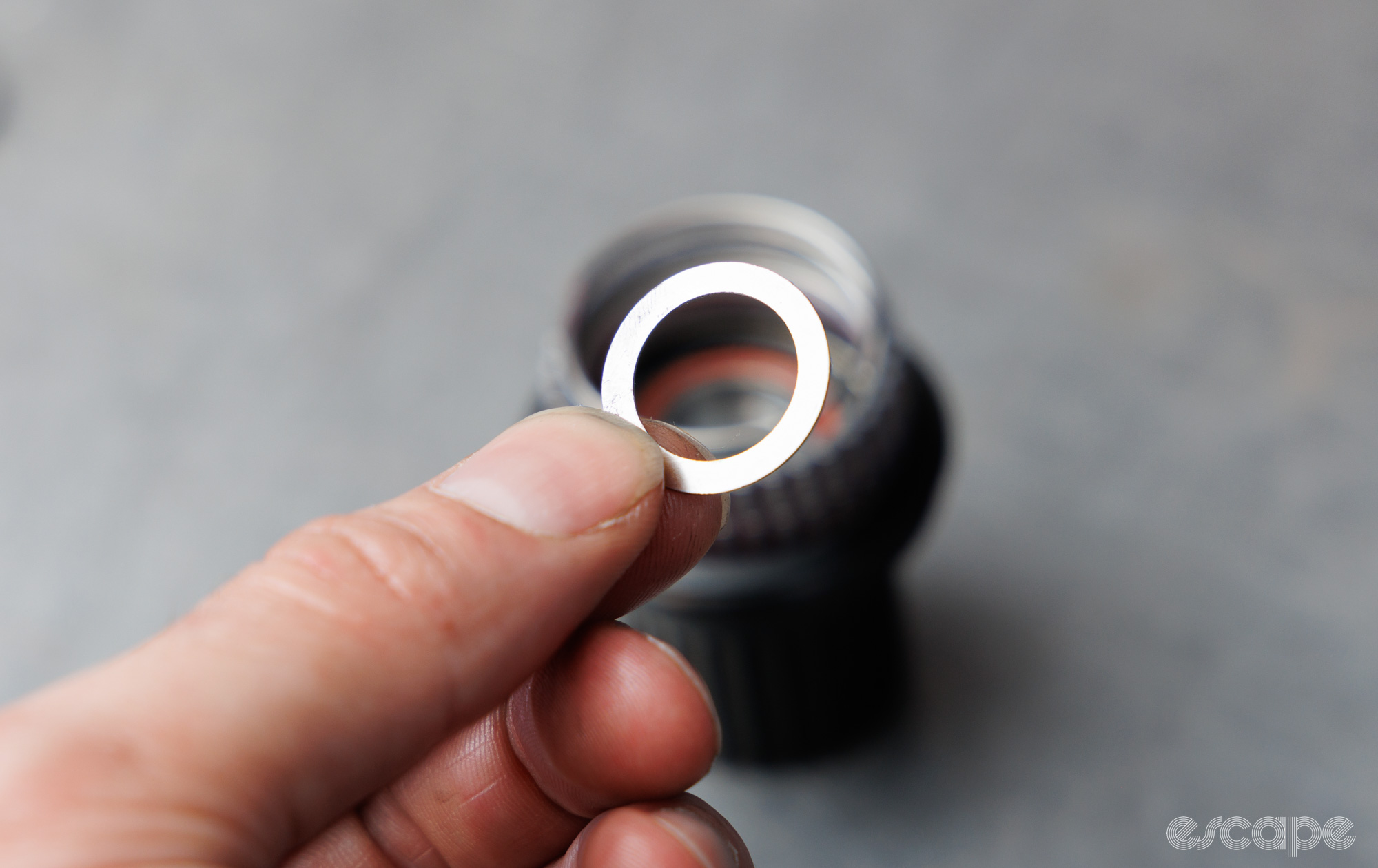 A small steel washer is held between two fingers. 