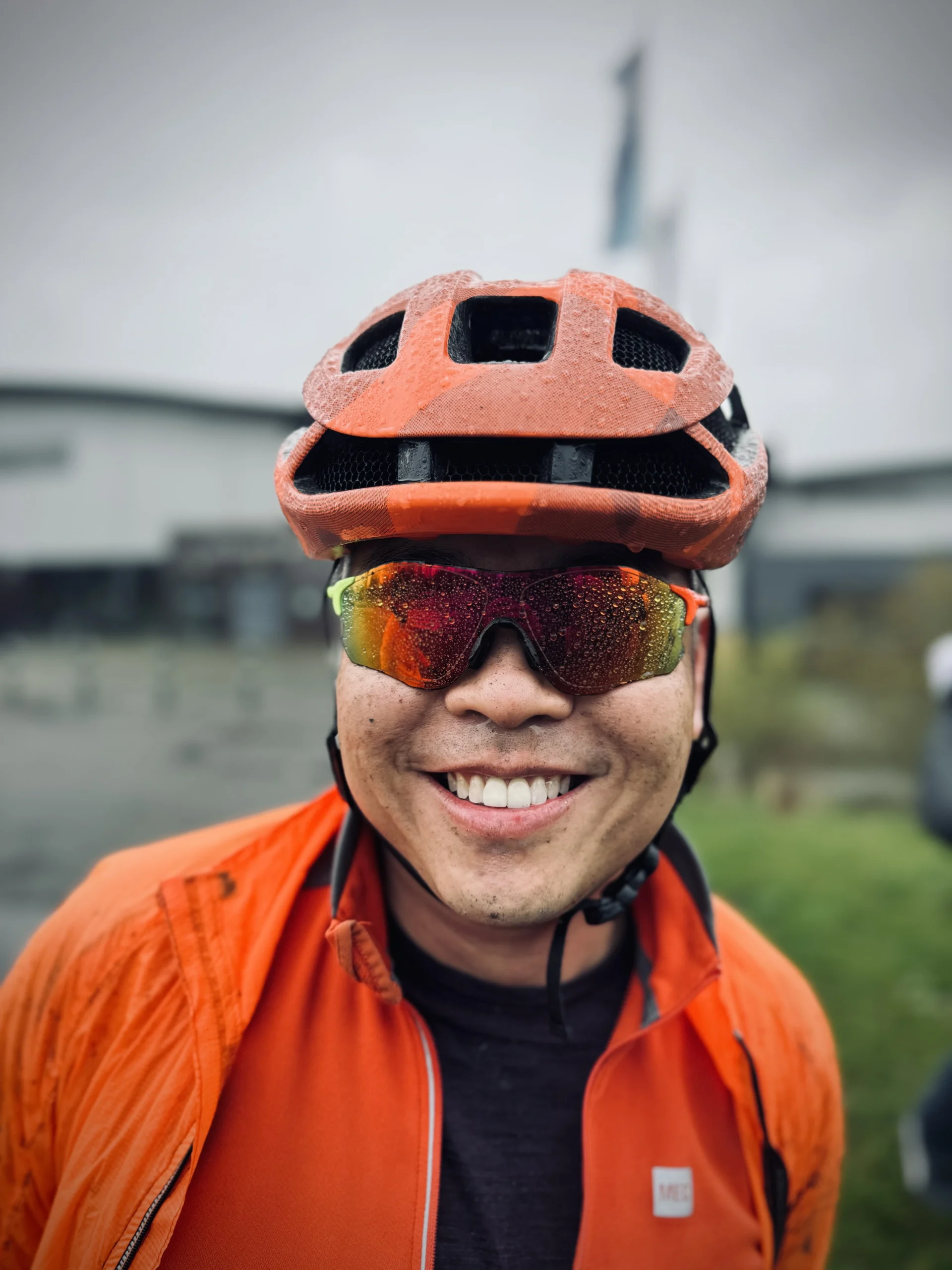 A portrait of Geoff Liu, face spackled with mud and dirt from riding in the rain