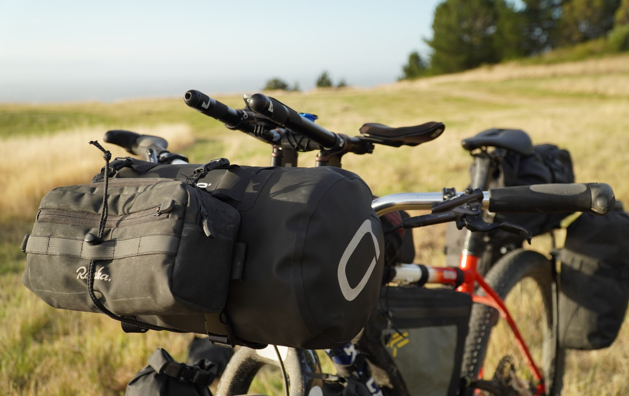 The Rapha handlebar bag is cinched down over another bag on the front of the bike, just below the aero extensions.