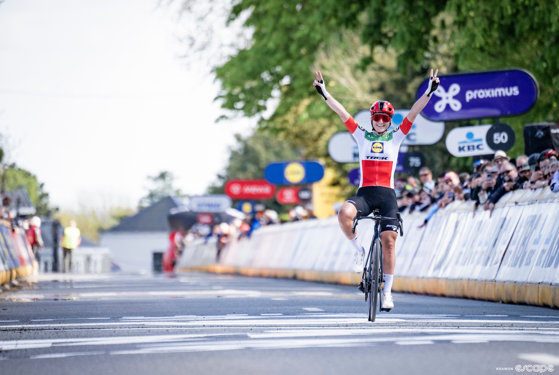 Elisa Longo Borghini raises her arms as she wins a cycling race.