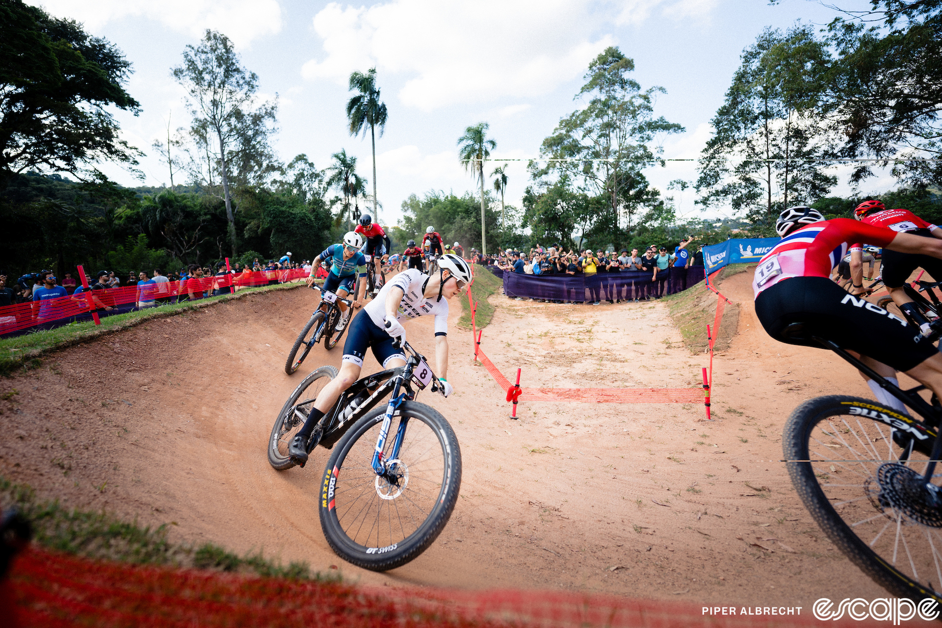 Riders navigate a pump track at the Mairiporã World Cup. The dirt is red clay and looks like a golf sand trap.