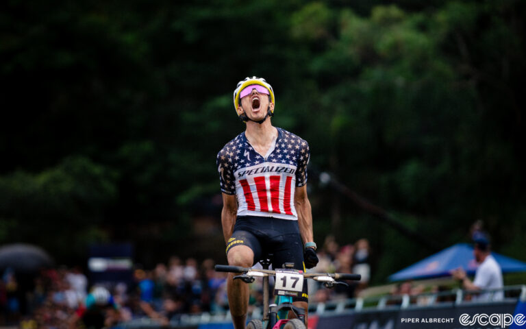 Chris Blevins throws his head back in celebration as he crosses the finish line to win the opening round of the 2024 Mountain Bike World Cup.
