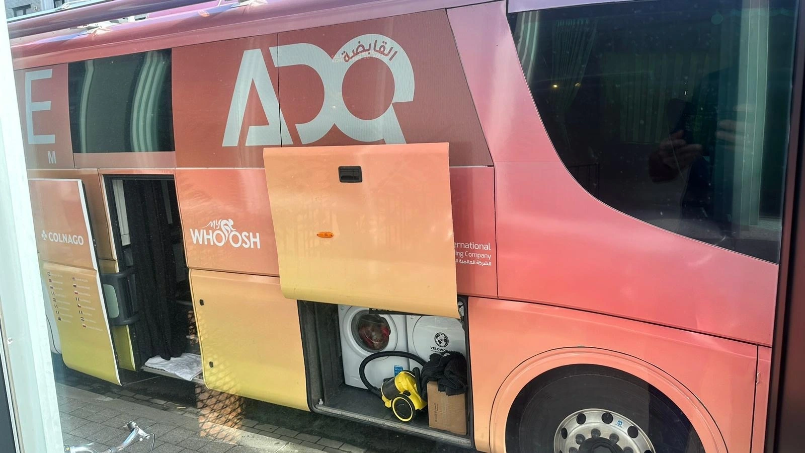 A washer and dryer combo in one of the storage bays of the ADQ team bus