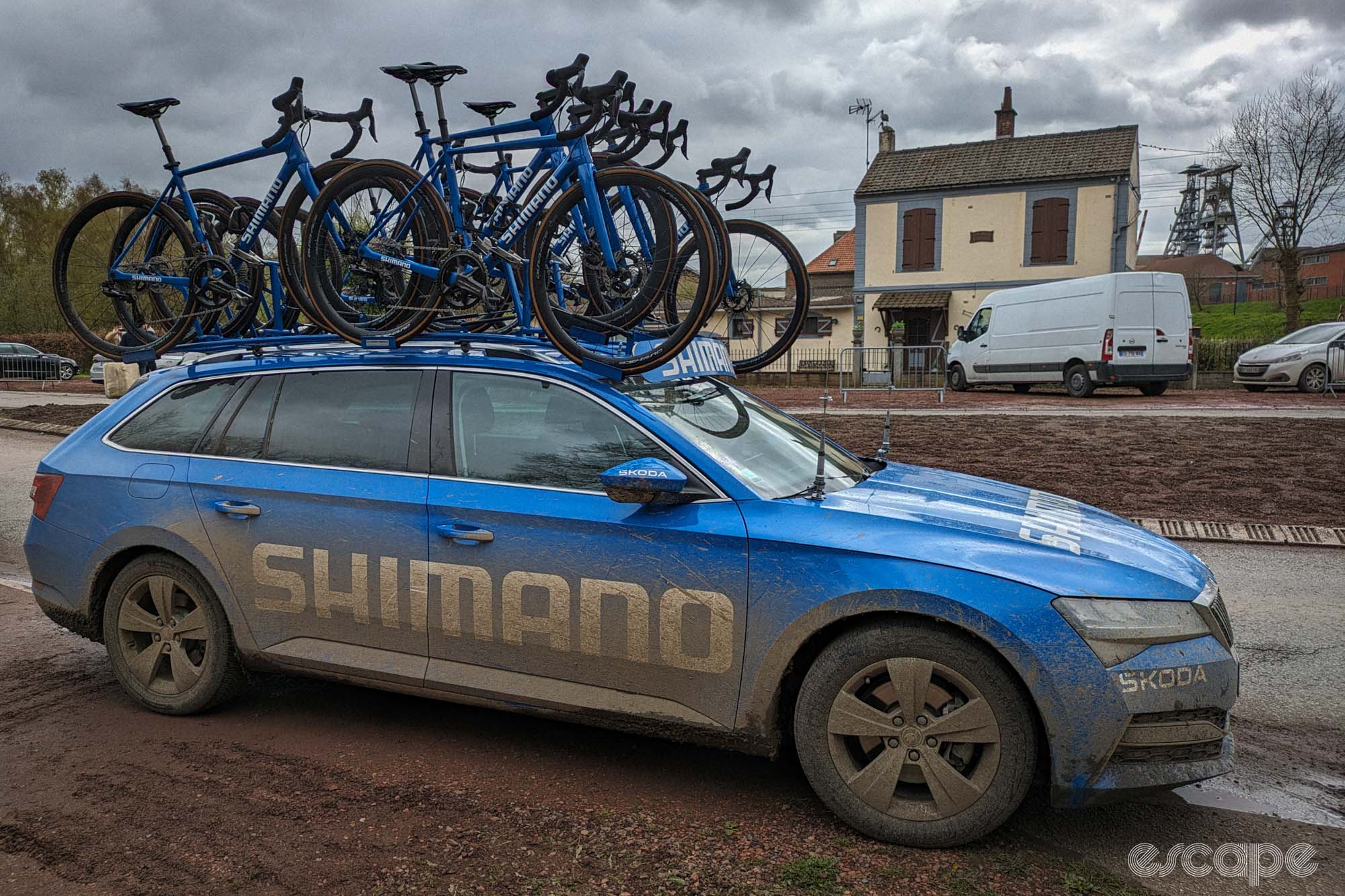 The Shimano neutral service car at the end of the day. Its bright blue paint is now thoroughly covered with brown mud and the white Shimano logo is grey-brown.