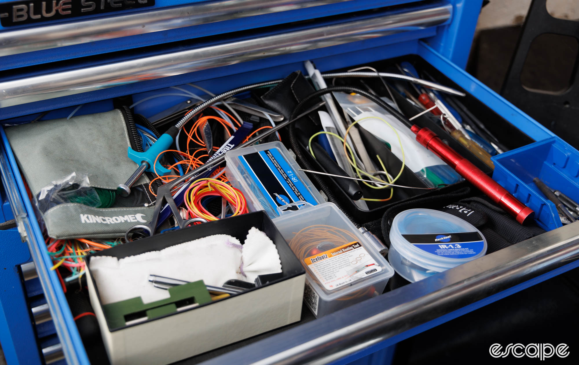 A toolbox draw with a mess of wires and various tools. 