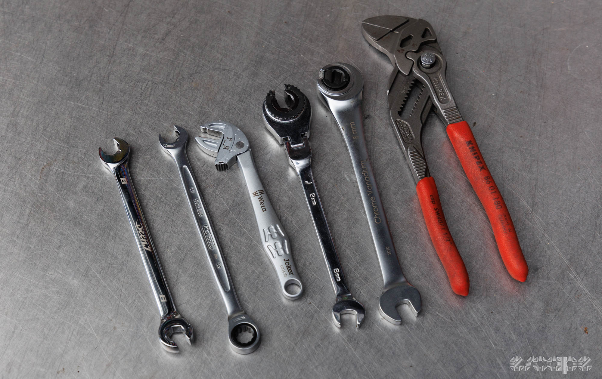 Six different tools on a bench, all with the purpose of offering a ratcheting function with 8 mm disc brake hose nuts.