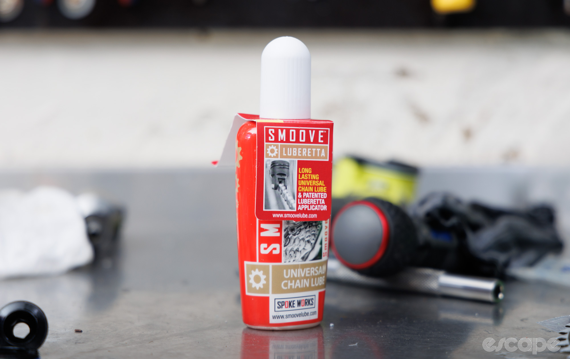 A bottle of Smoove chain lube sits on a workbench. 