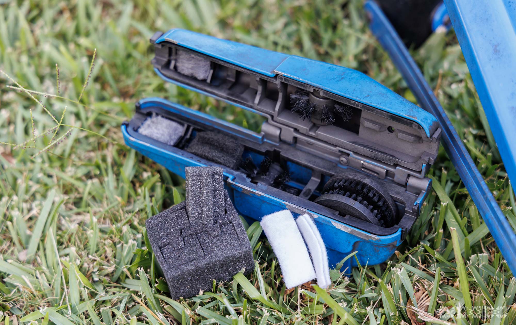 Park Tool CM-25 chain cleaner on grass with the new sponge kit, now out of its packaging. The legs of a Park Tool repair stand sit in the photo. 