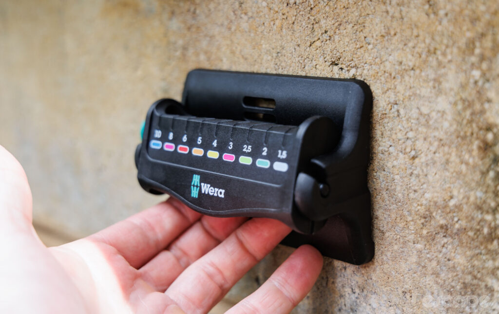 The same Wera holder is held against a wall to show it works in a wall-mounted application. 