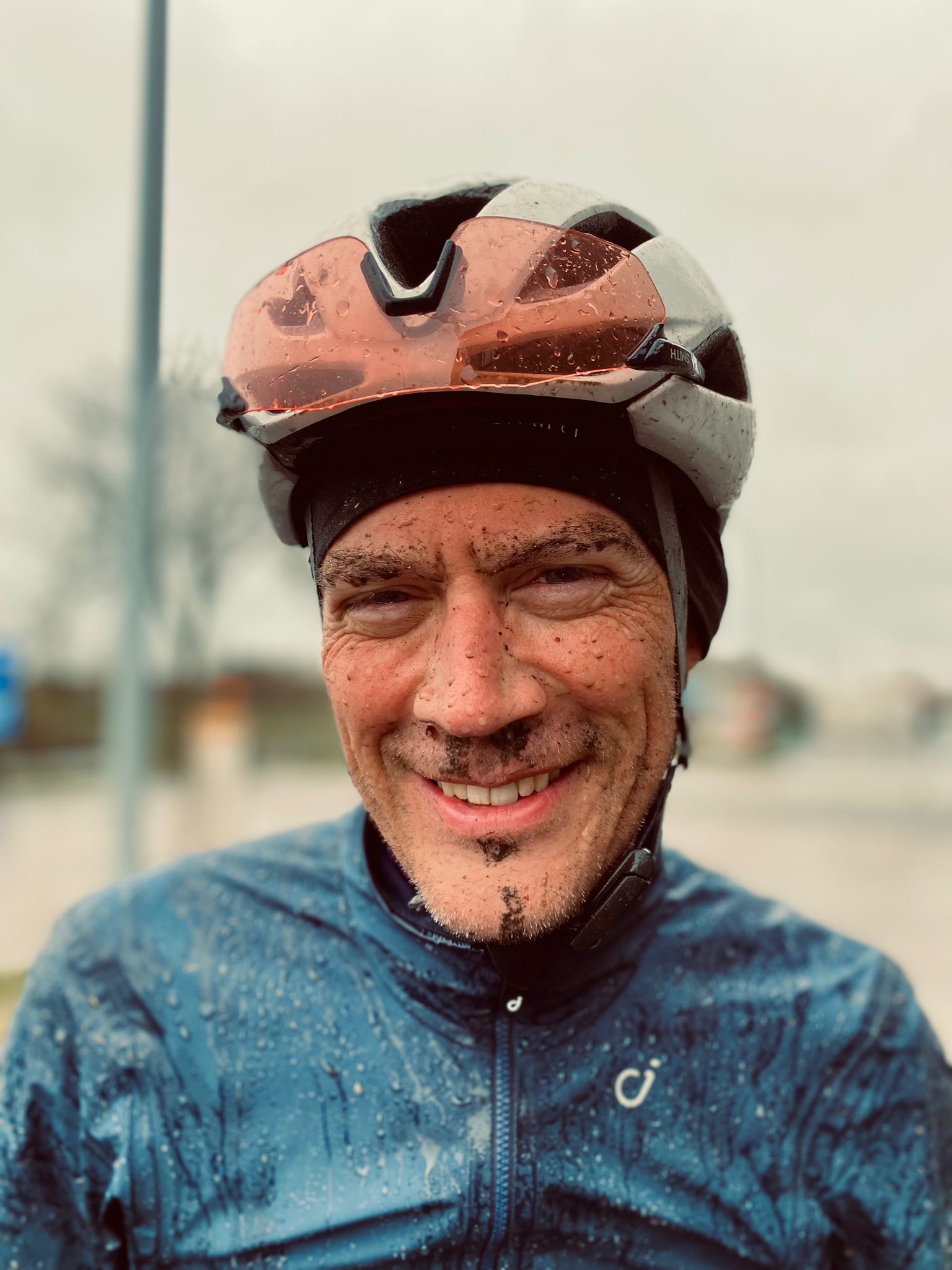 A portrait of Todd Markelz, face spackled with mud and dirt from riding in the rain
