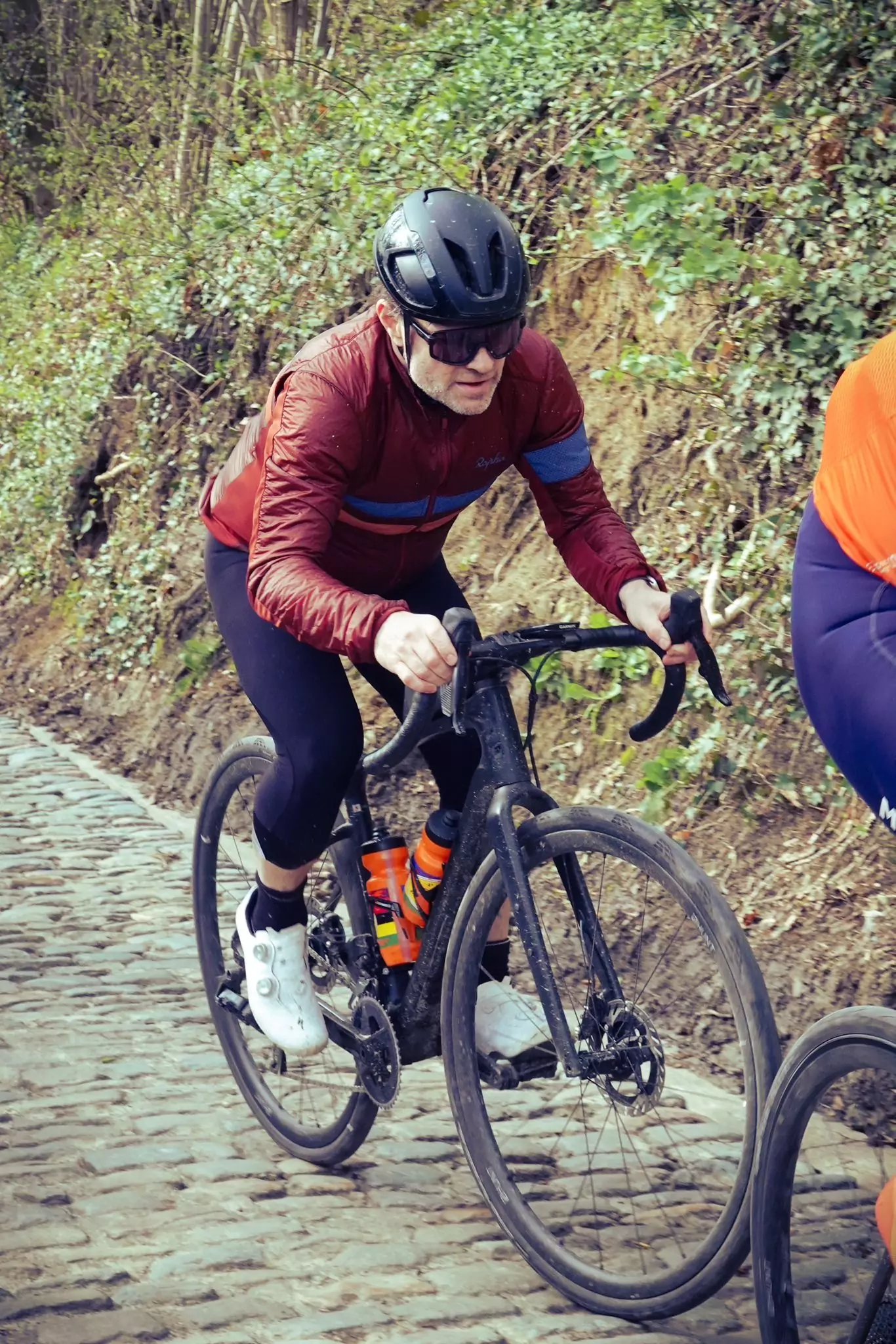 An action photo of Noah Greenhill riding up the Koppenberg