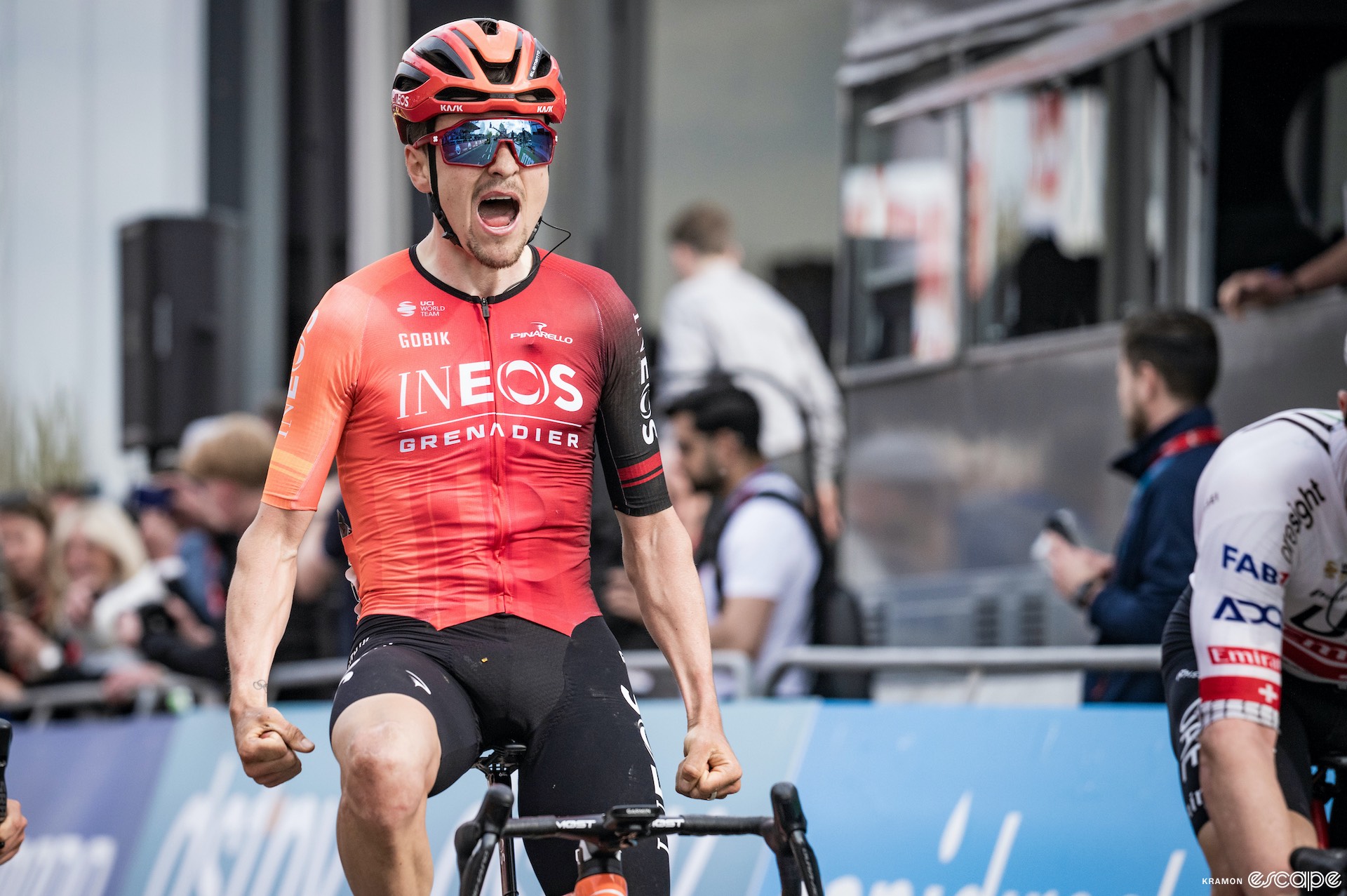 Tom Pidcock posts up for the win at the Amstel Gold Race. His mouth is open in a shout as he clenches his fists at his side after winning the small group sprint.
