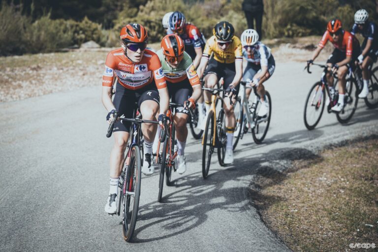 Demi Vollering leads a group of climbers up an ascent during La Vuelta while wearing the red leader's jeresy.