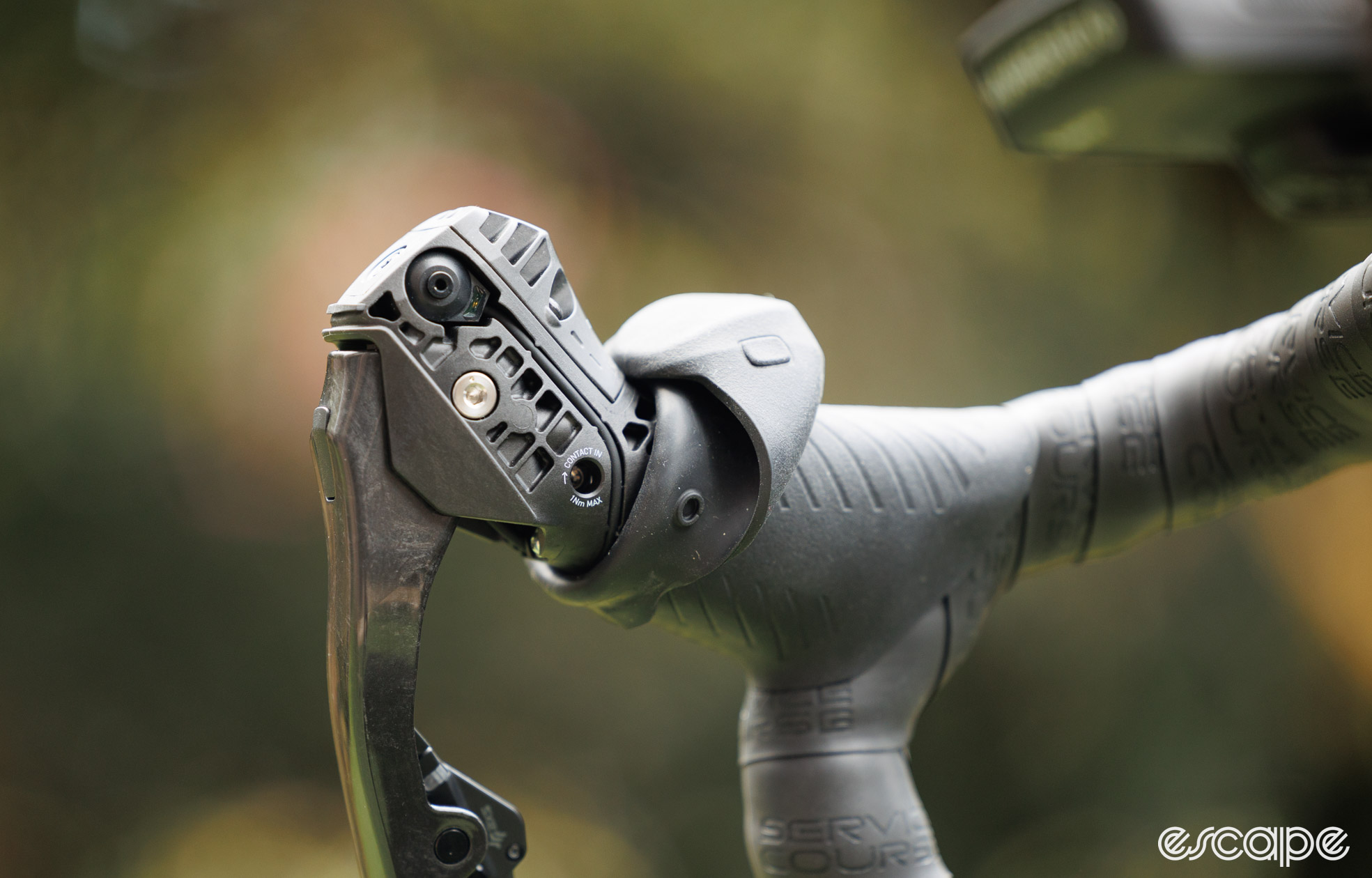  SRAM Red AXS shifter with the rubber hood peeled back to show the bonus button and contact point adjustment screw. 