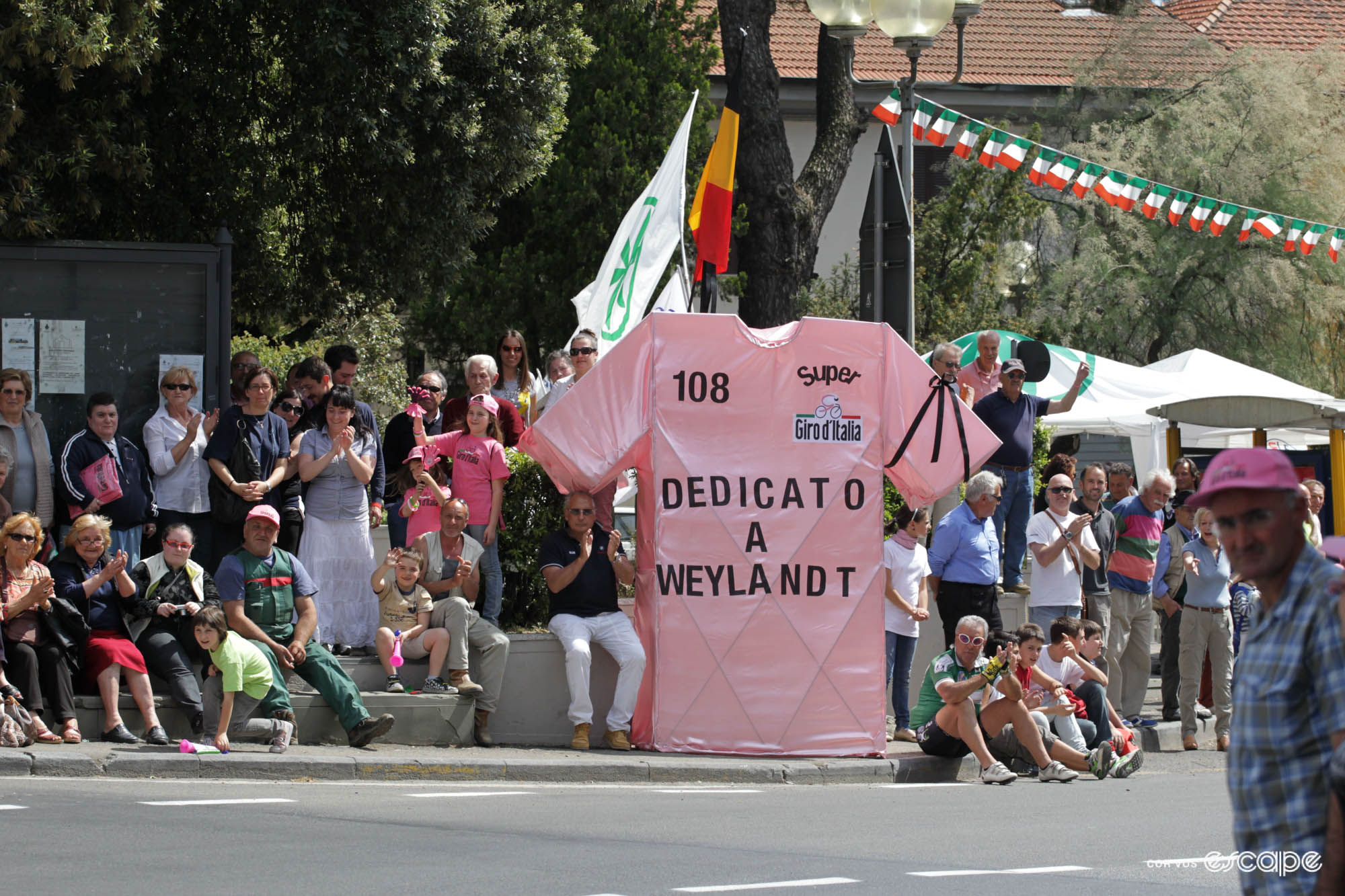 A roadside sign at the 2003 Giro d'Italia: a pink jersey, the number 108 on it, and the message 'Dedicata a Weylandt' on it. 