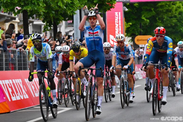 Tim Merlier sits up and makes a W sign after winning a furious bunch sprint on stage 3 of the 2024 Giro d'Italia.