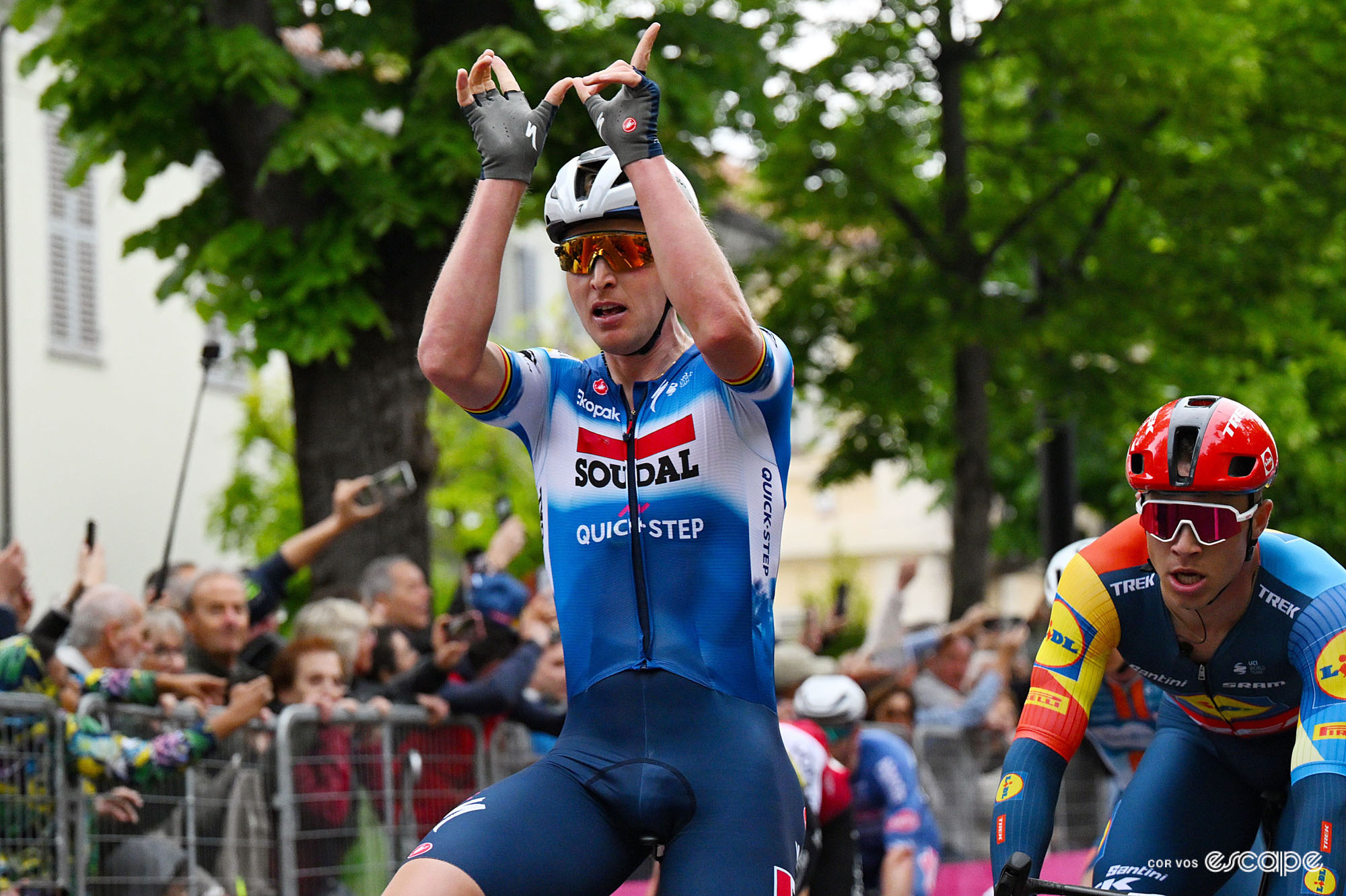 Tim Merlier crosses the finish line of the third stage of the 2024 Giro, hands raised in a W shape.