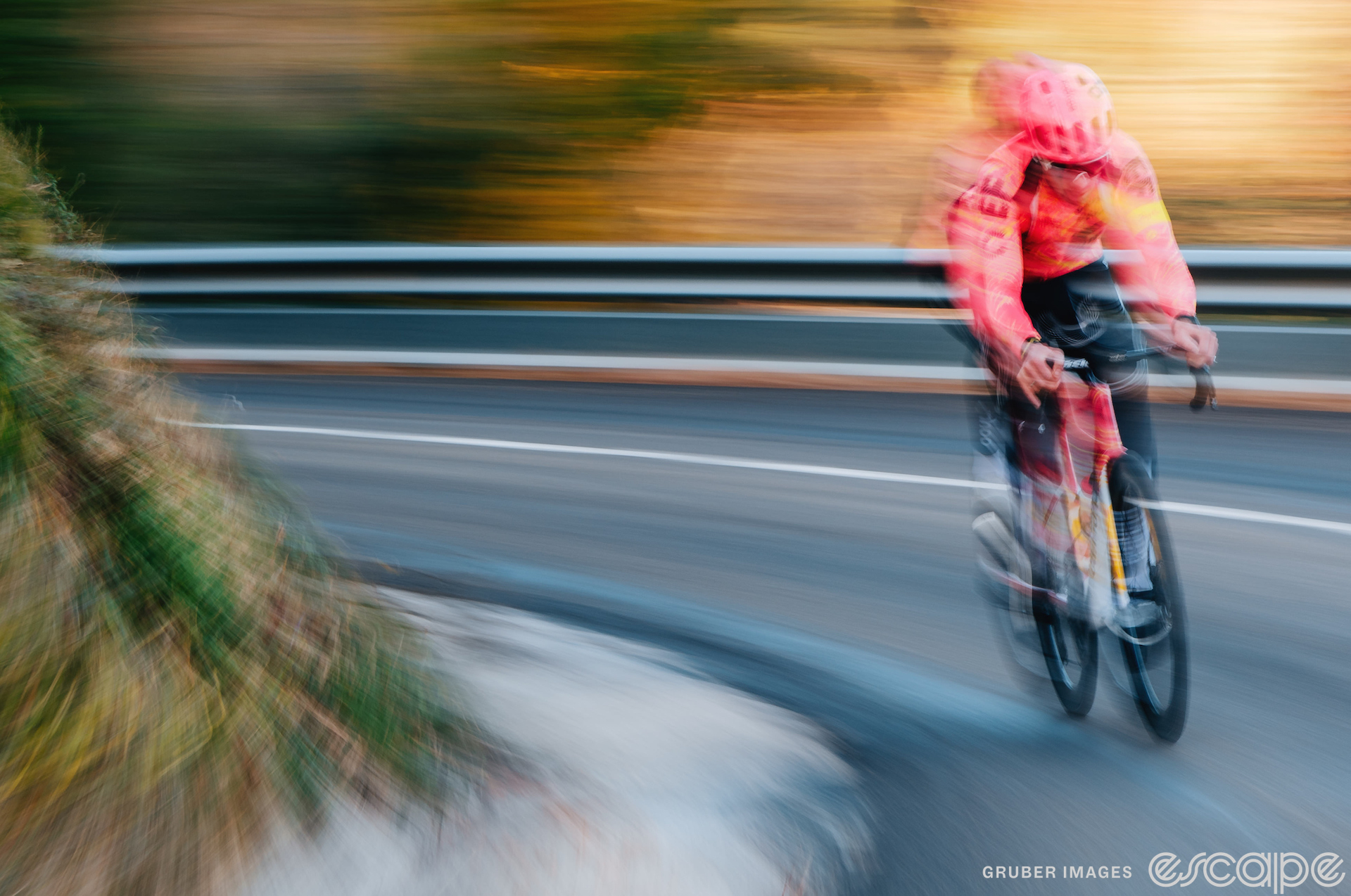 An EF cyclist accelerates around a corner. He's alone, and the shot has a speed blur that results in a kind of double-exposure.