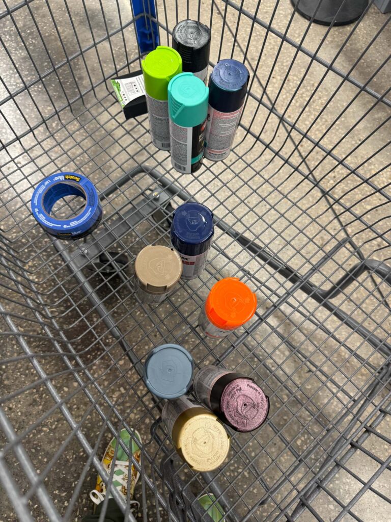 Cans of spraypaint in a shopping trolley.