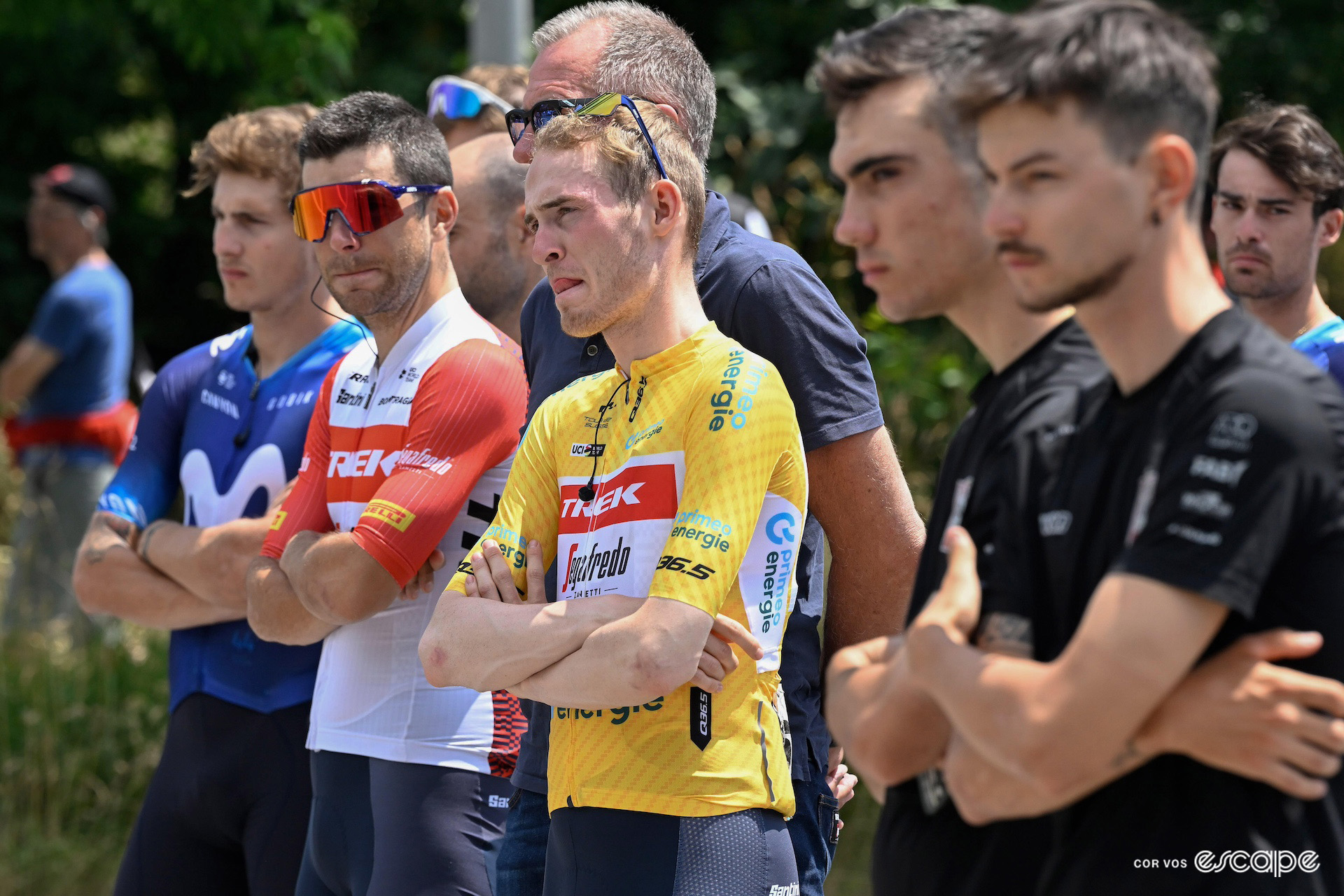 An emotional Mattias Skjelmose stands with his arms crossed in the yellow jersey of race leader on the morning after Gino Mäder's Tour de Suisse crash.