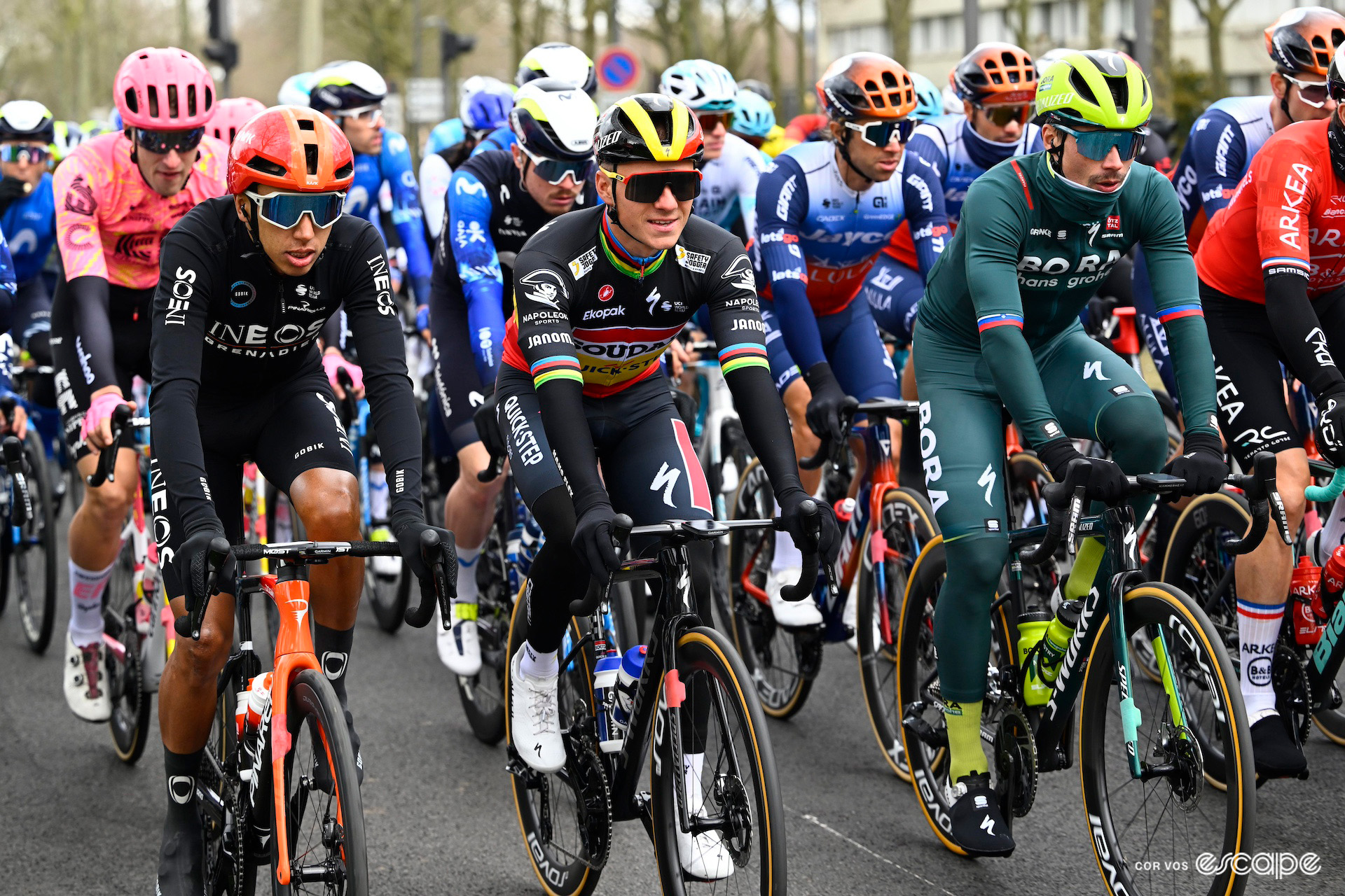 Egan Bernal, Remco Evenepoel and Primož Roglič, all well wrapped up against the cold, ride at the front of the peloton at the start of Paris-Nice 2024.