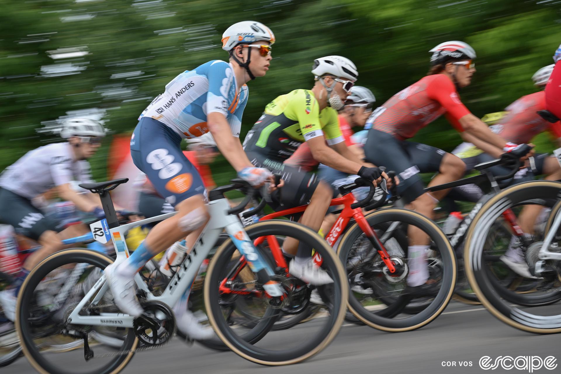 Frank van den Broek climbs in a pack of racers. They're somewhat speed-blurred, but his blue-and-white DSM jersey is in sharp focus.