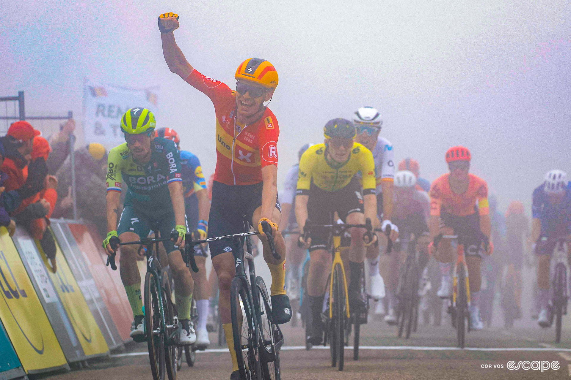 Magnus Cort punches the air in celebration as he wins the uphill sprint shrouded in fog on stage 2 of the 2024 Critérium du Dauphiné.