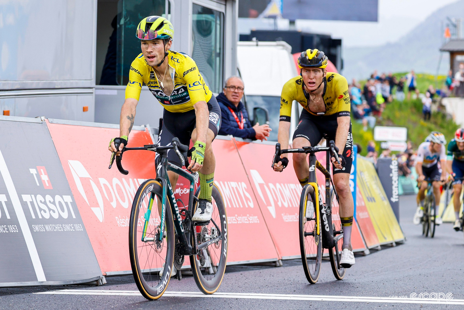 Primož Roglič in the yellow jersey crosses the line victorious on stage 7 of the 2024 Critérium du Dauphiné but unable to celebrate with Matteo Jorgenson glued to his wheel.