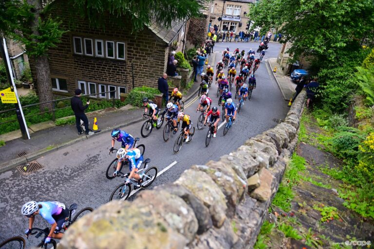 The women's peloton races through a small British town.