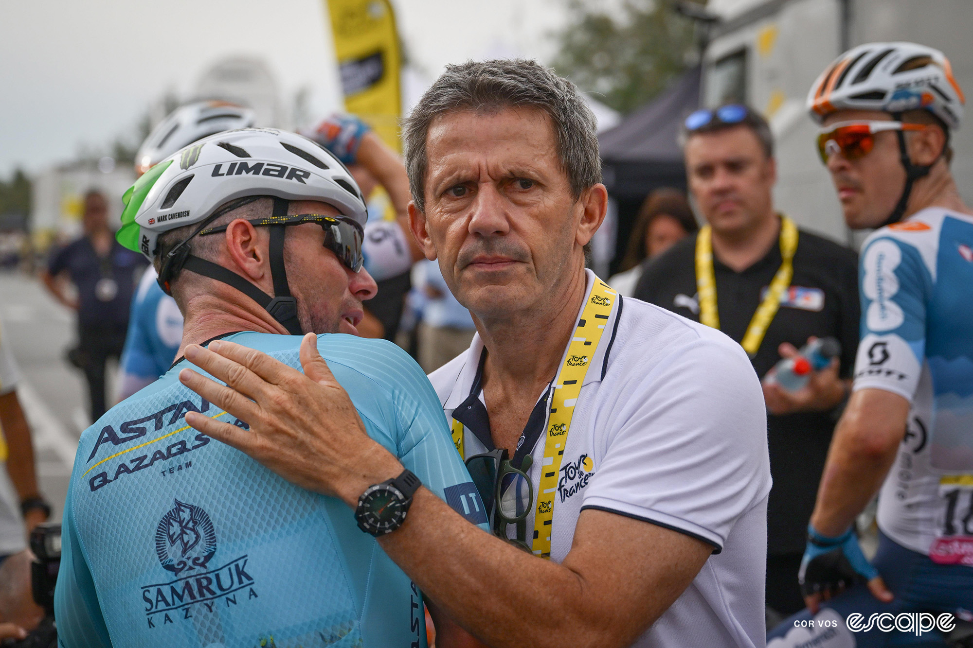 Cavendish is comforted/congratulated by a member of Tour de France staff.