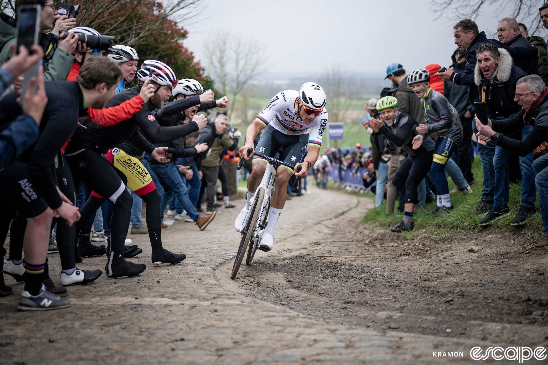 Mathieu van der Poel tops the Oude Kwaremont climb in the 2024 Tour of Flanders. The world champion leans into the turn, using the gutter as a chicane, as fans lean in close to cheer.