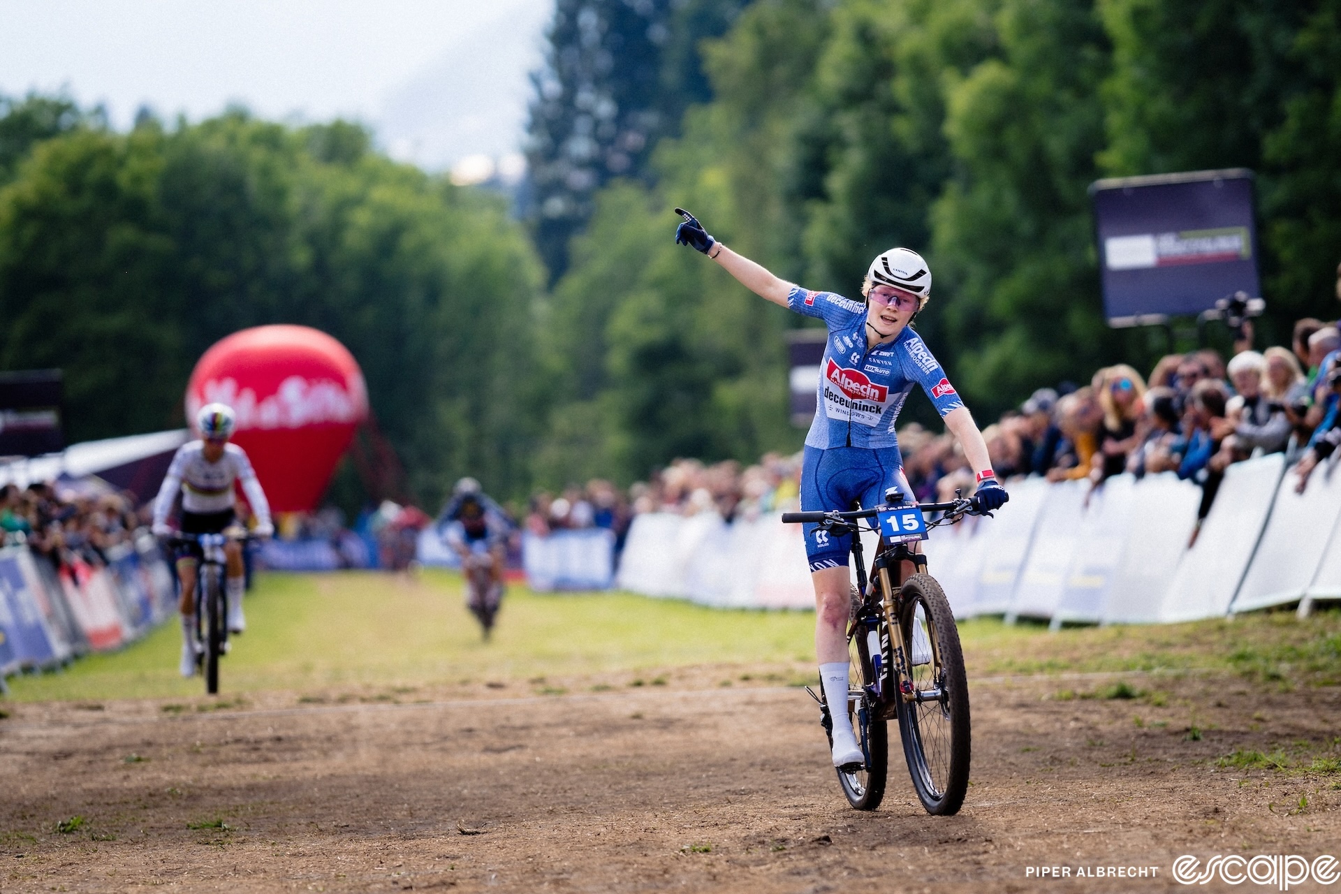 Puck Pieterse raises an arm in the air as she pulls away from Pauline Ferrand-Prévot to win the XCC at the Val di Sole Mountain Bike World Cup.