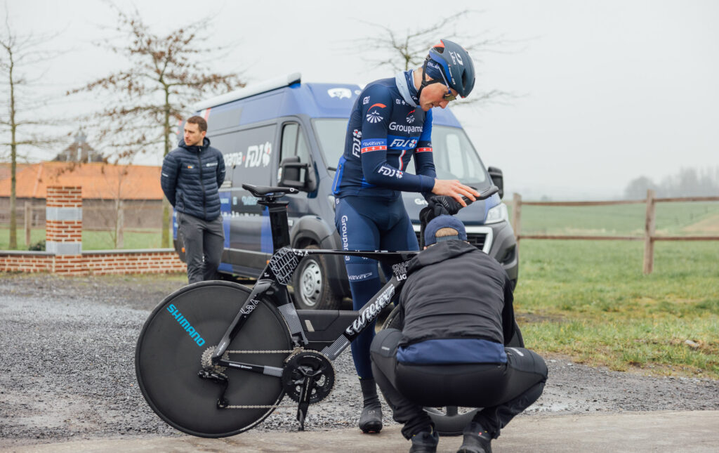 The image shows Stefan Kung and a mechanic checking out the new bike.